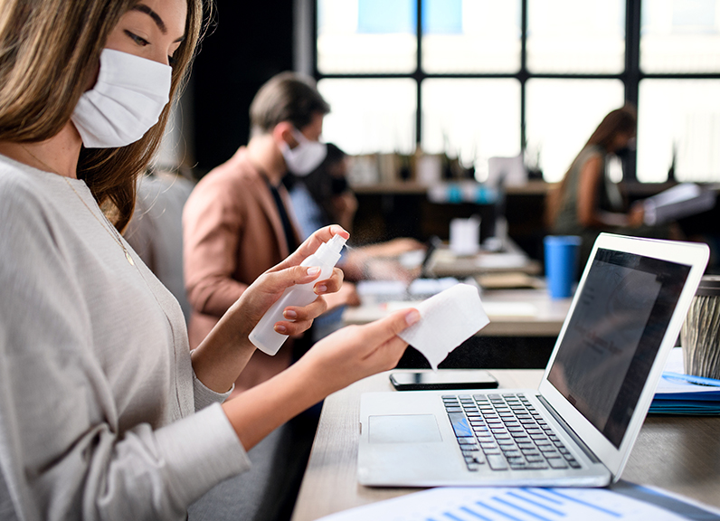 mujer sanitizando sus implementos de trabajo en la oficina